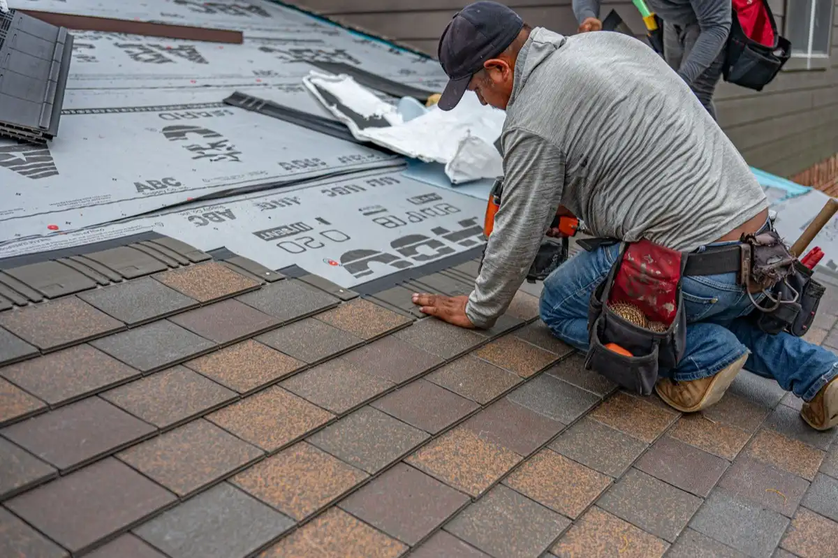 Roofing installer fastening shingles over new underlayment in Baltimore, MD